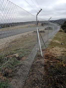 Una valla de alambre rodea un campo al lado de una carretera.