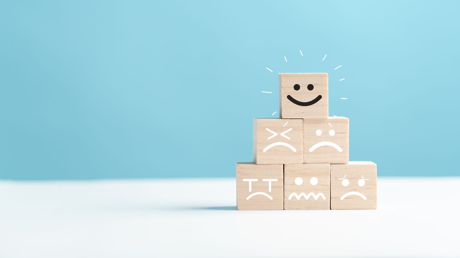 Cubes en bois avec émoticones sourire, tristesse et autres émotions.