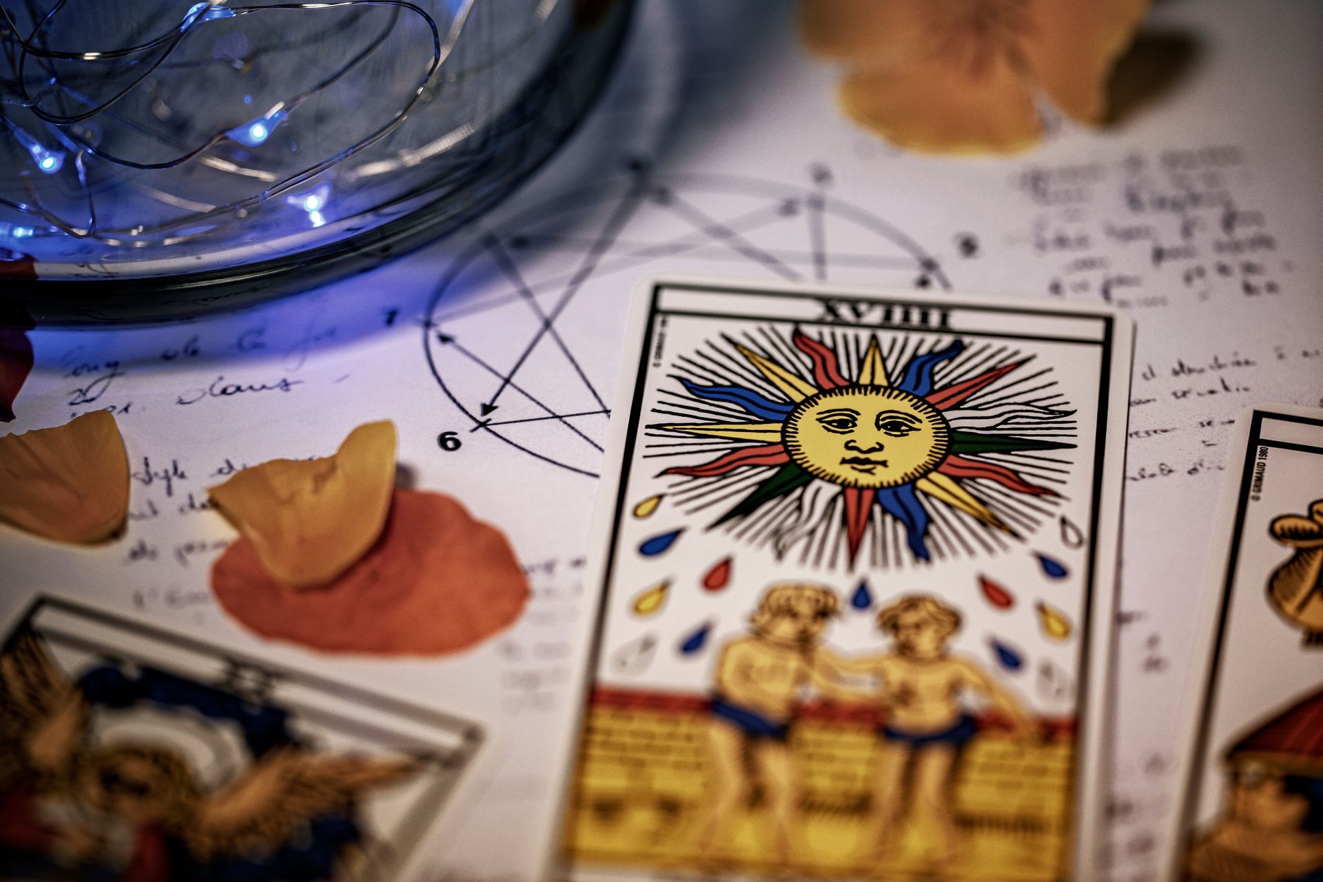 Carte de tarot posée sur une table avec d'autres cartes, des fleurs et un bocal en verre.