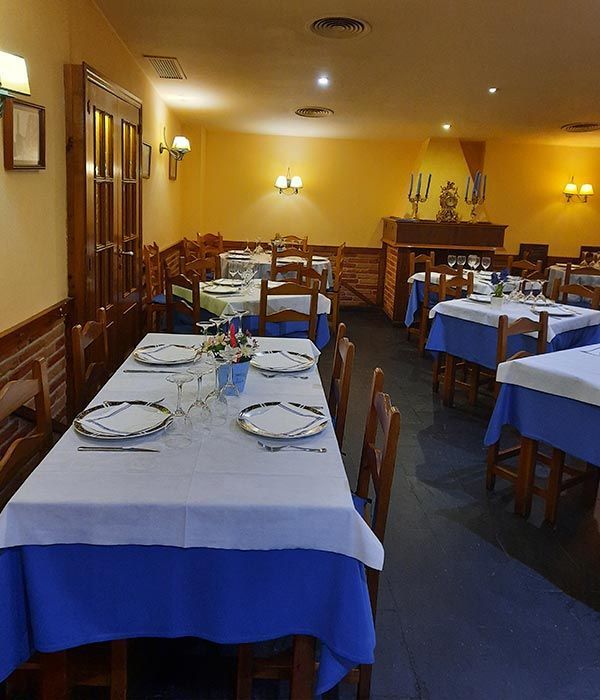 Comedor vacío de un restaurante con mesas vestidas de blanco y azul y sillas de madera.