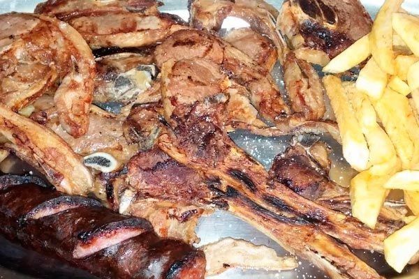 Pescado a la parrilla y patatas fritas en una bandeja, con trozos chamuscados y patatas fritas doradas.