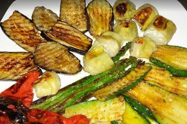 Verduras variadas a la parrilla servidas en un plato blanco, que incluyen berenjena, calabacín, pimientos y champiñones.