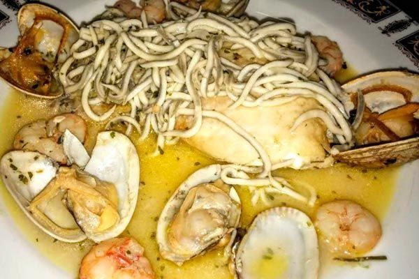 Pasta con mariscos, mejillones y camarones en una salsa amarilla cremosa, cubierta con fideos.