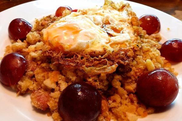 Postre cubierto con salsa cremosa y uvas rojas en un plato blanco.