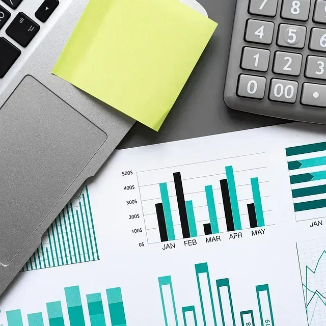 Una calculadora y una computadora portátil están sobre una mesa con gráficos.