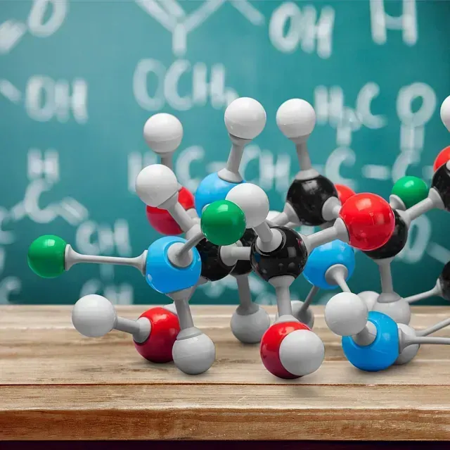 Un modelo de una estructura química está sobre una mesa frente a una pizarra.