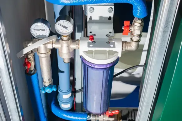 Un primer plano de un filtro de agua rodeado de tuberías y medidores.