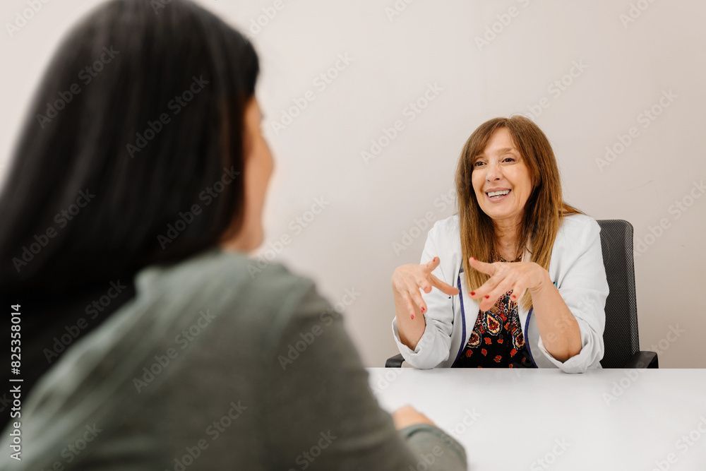 Eine Kosmetikerin sitzt an einem Tisch und unterhält sich mit einer Kundin.