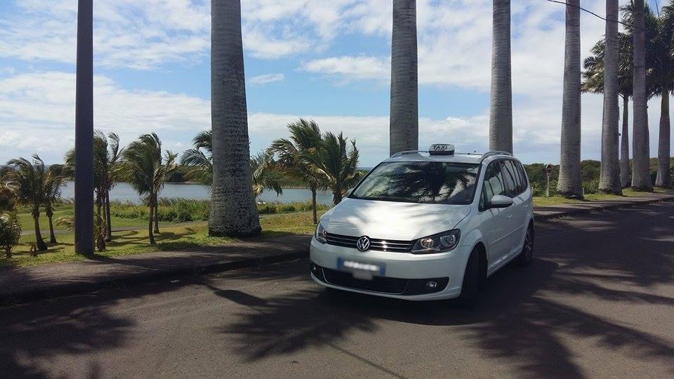 Taxi blanc sur la route devant des palmiers