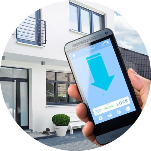 Une main tient un smartphone affichant une application de sécurité pour maison connectée avec une icône de cadenas bien visible, devant une maison moderne.