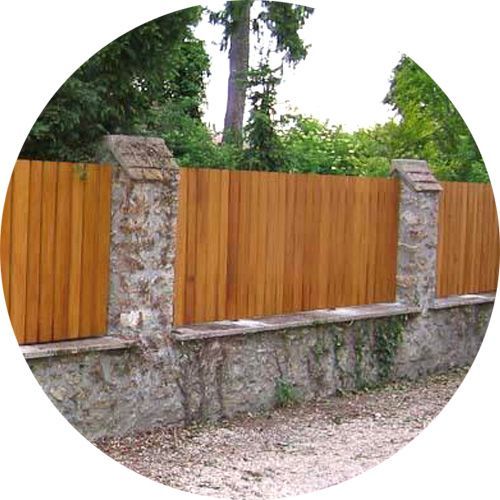 Palissade en bois et pilliers en pierres clôturant un jardin.