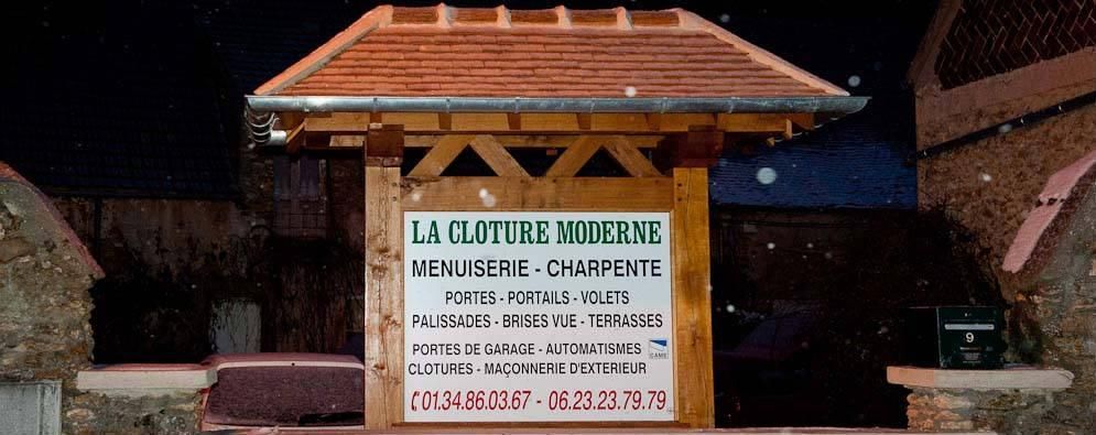 Une enseigne pour l'entreprise de menuiserie La Clôture Moderne, fixée sur une structure en bois, se détachant sur un fond sombre nocturne.