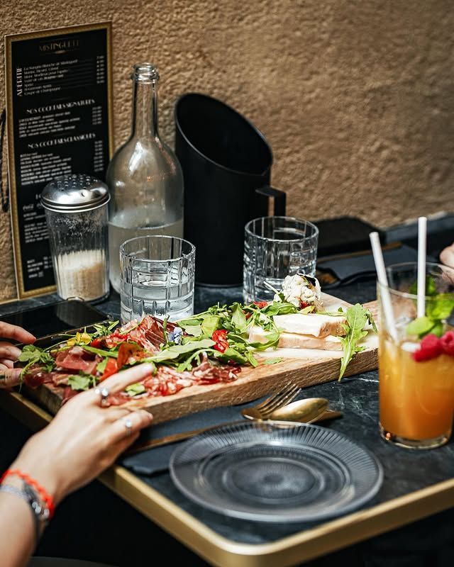 Table avec planche de charcuterie, boissons et menu.