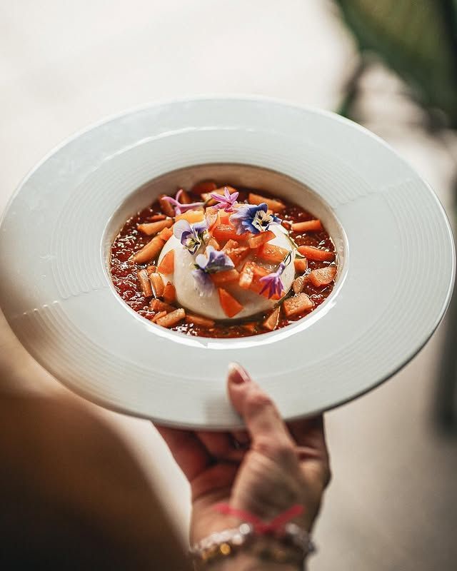 Une main tenant une assiette blanche avec un dessert en sauce.