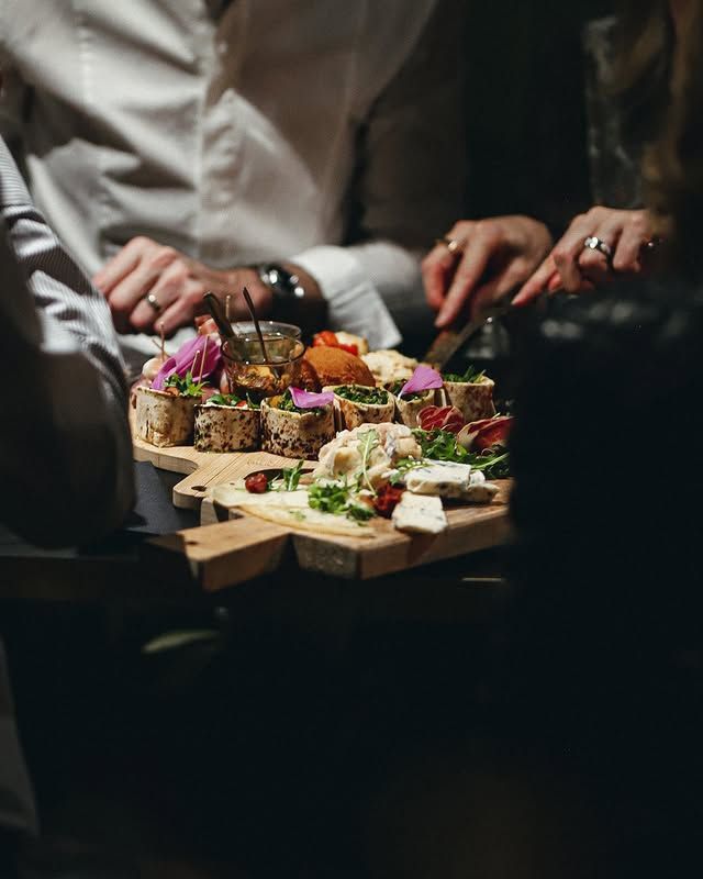 Des personnes se servent en amuse-gueules sur un plateau de service en bois en forme d'étoile.