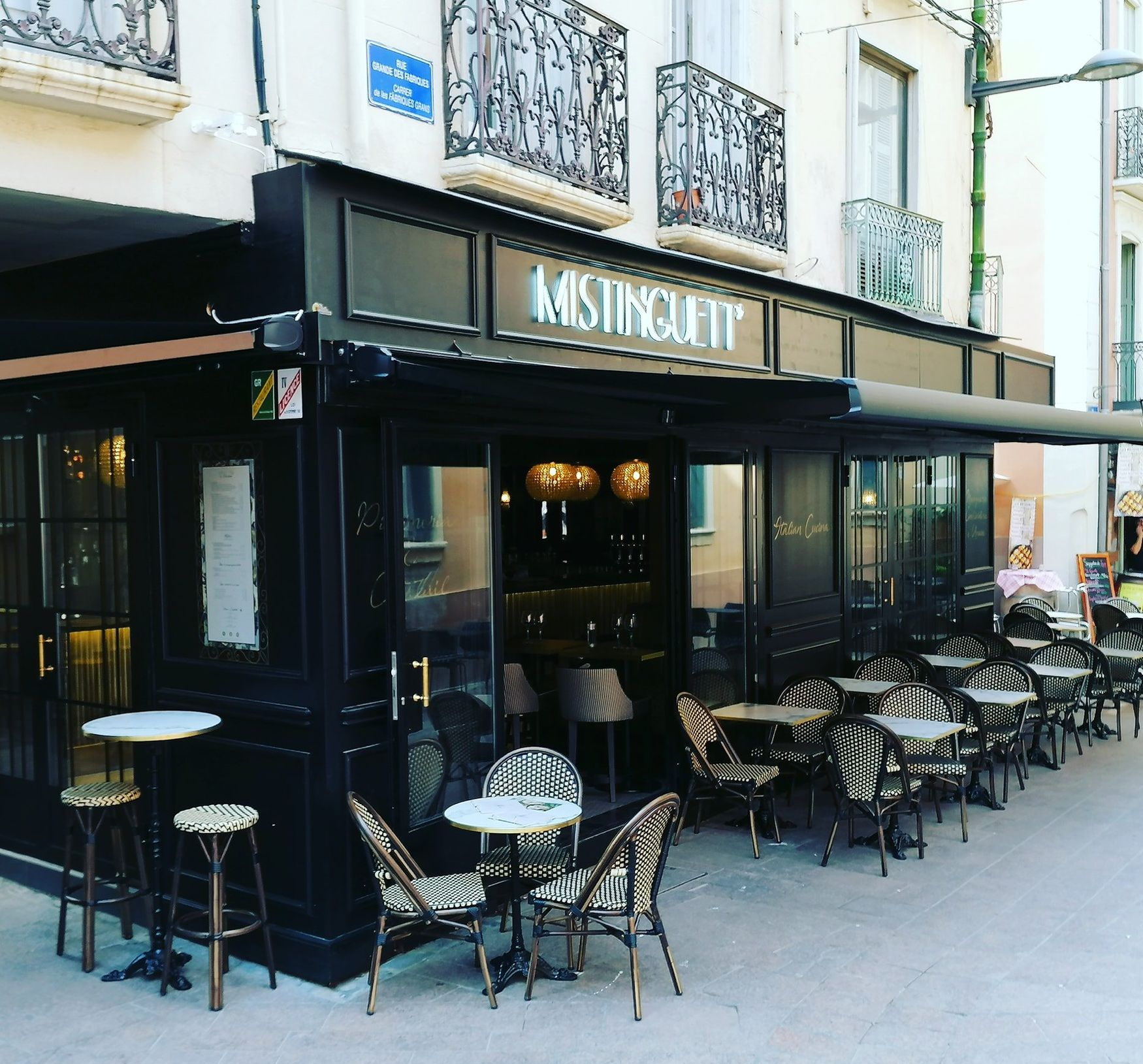 Restaurant à la façade noire, avec terrasse en centre-ville.