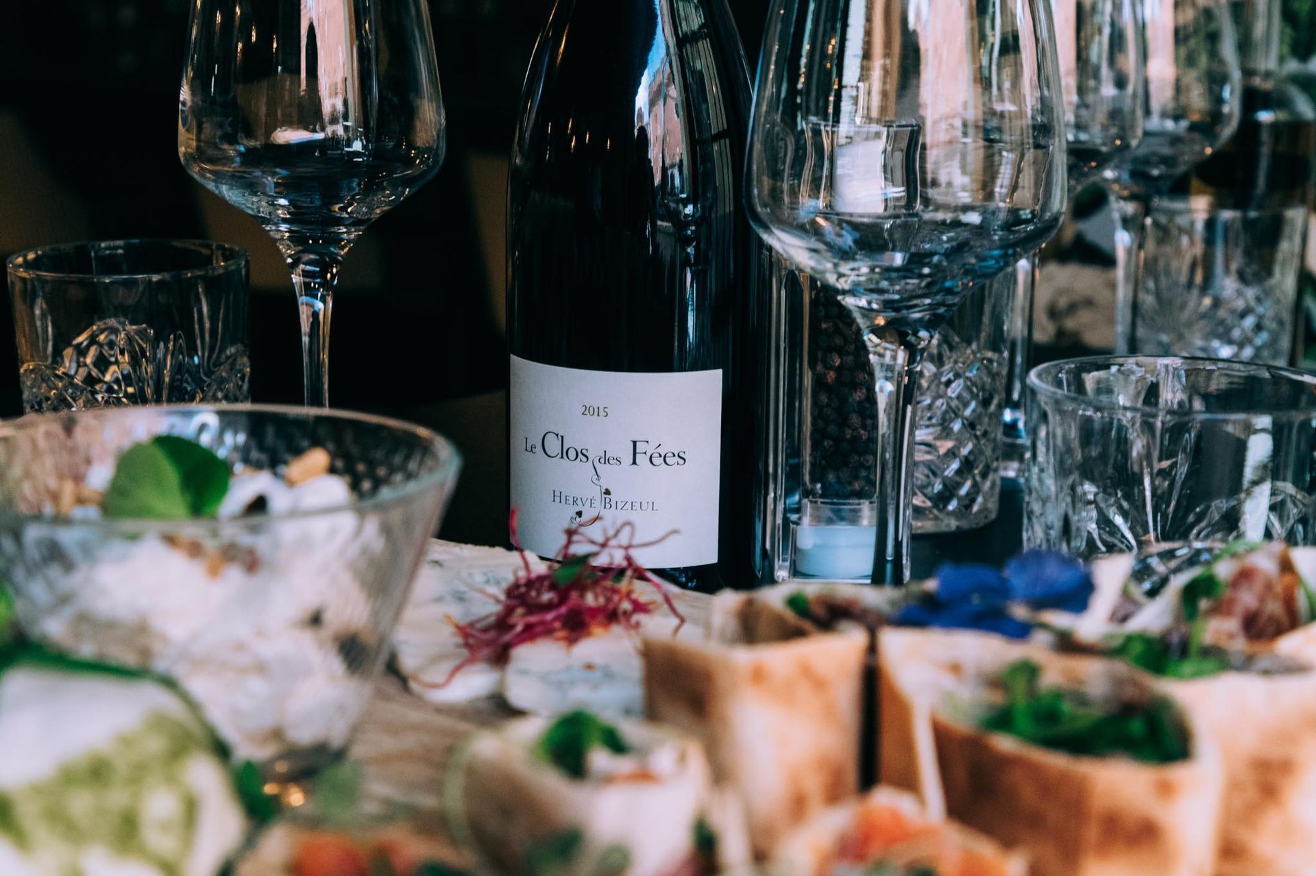 Bouteille de vin, verres et amuse-gueules sur une table.