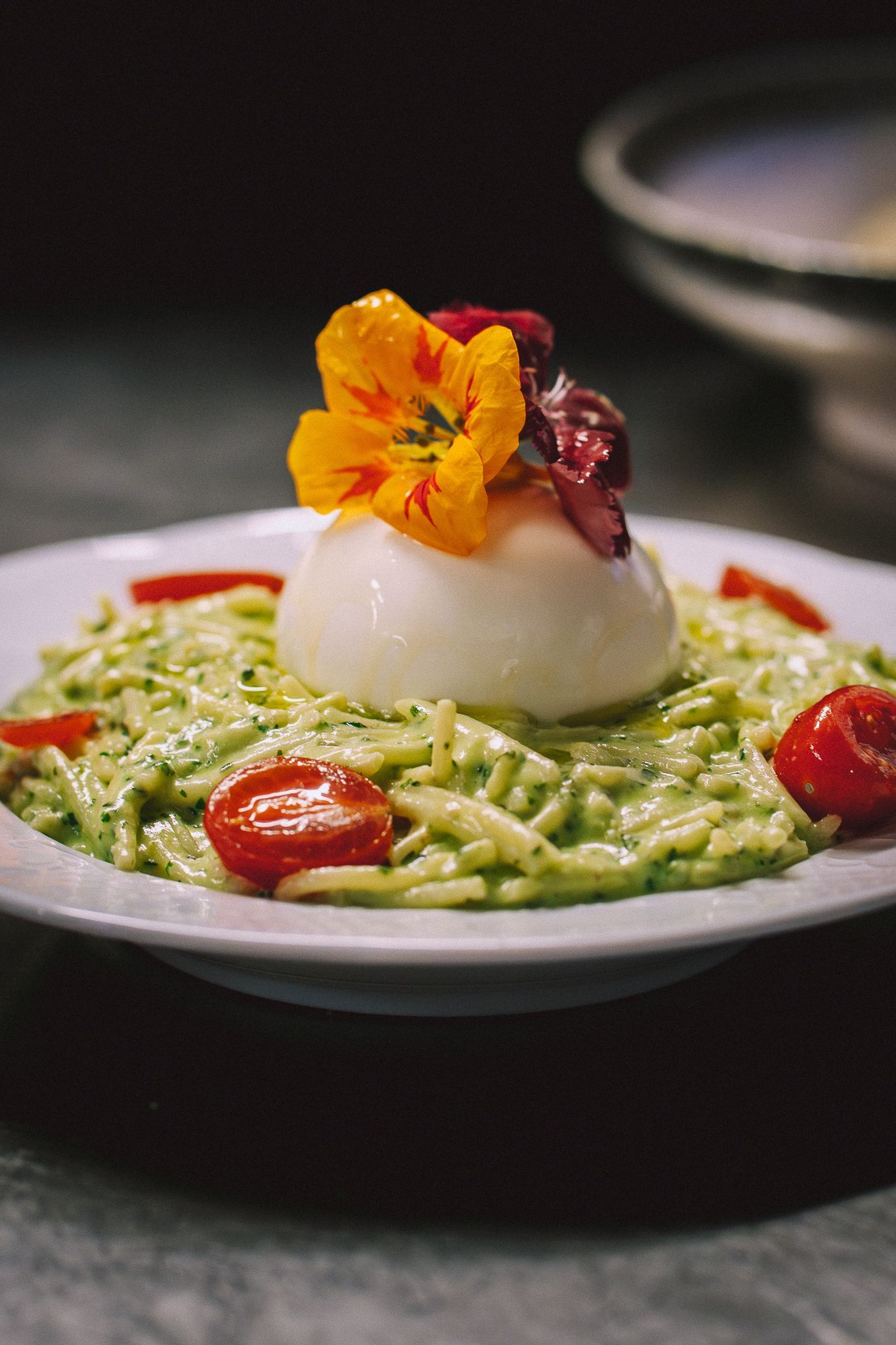Plat de pâtes à la burrata, aux tomates et aux fleurs comestibles.