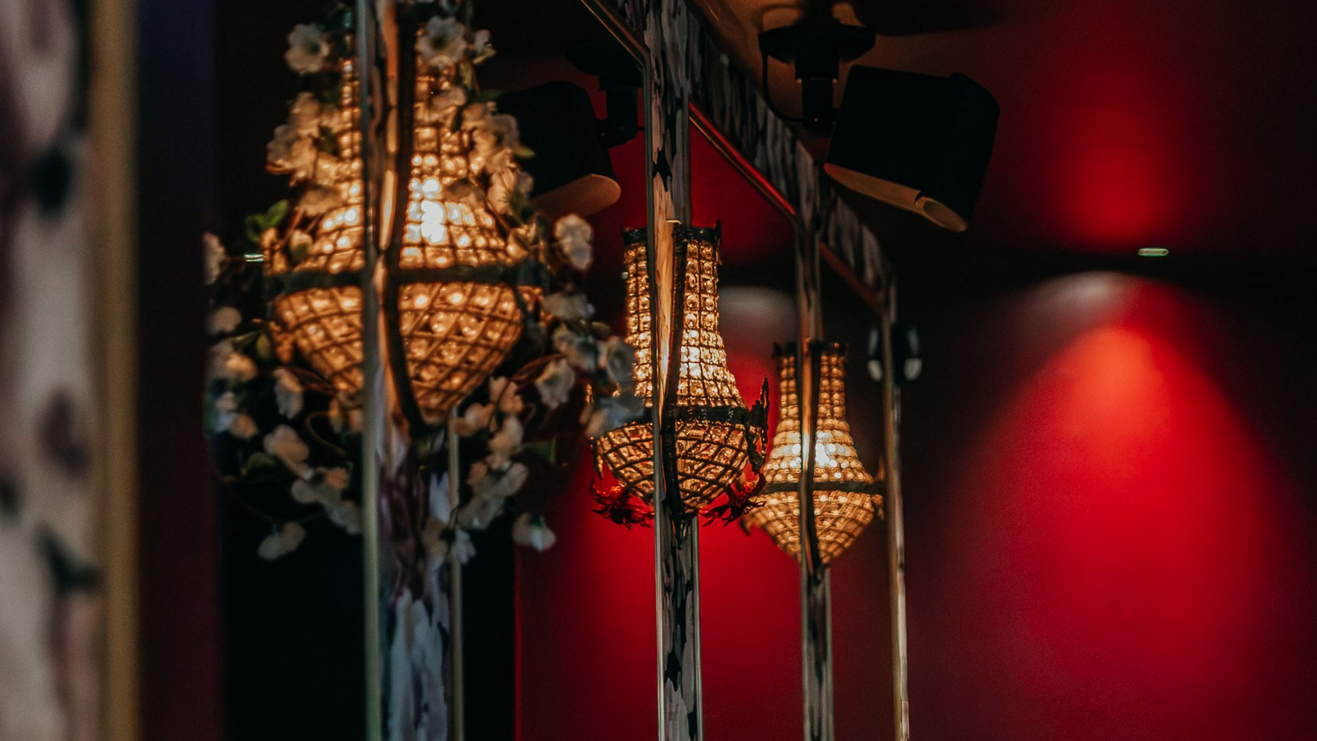 Extérieur d'un restaurant, avec une façade noire, des tables et des chaises sur un trottoir.