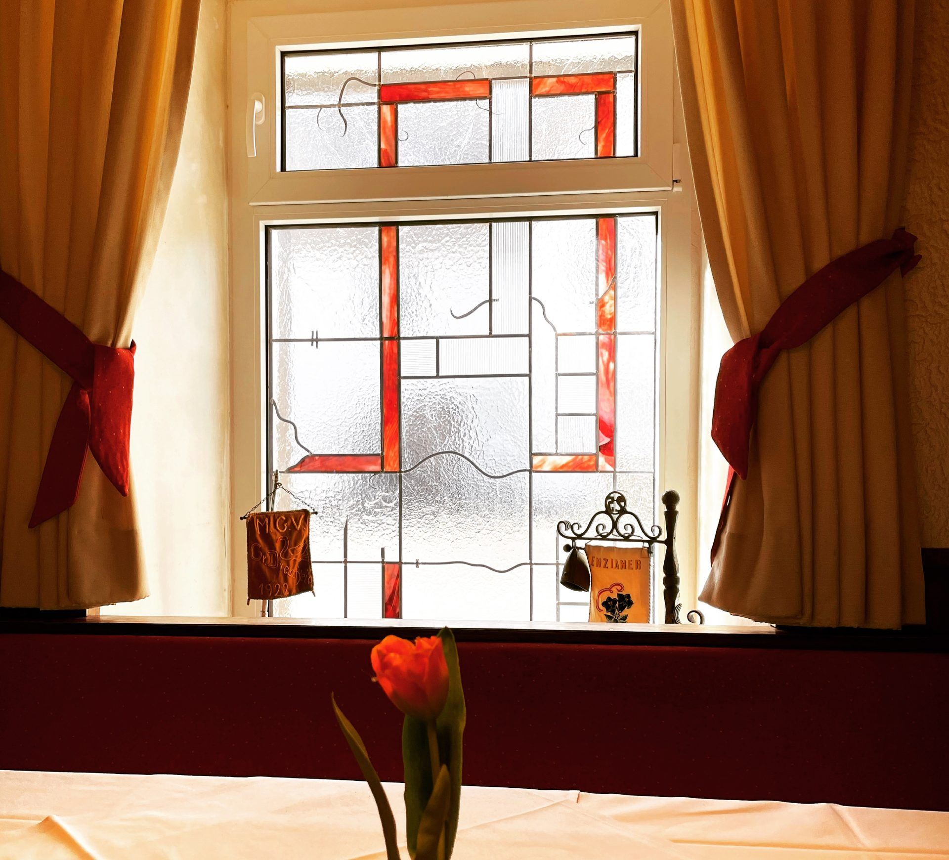 Ein Tisch mit einer Vase mit Blumen vor einem Buntglasfenster