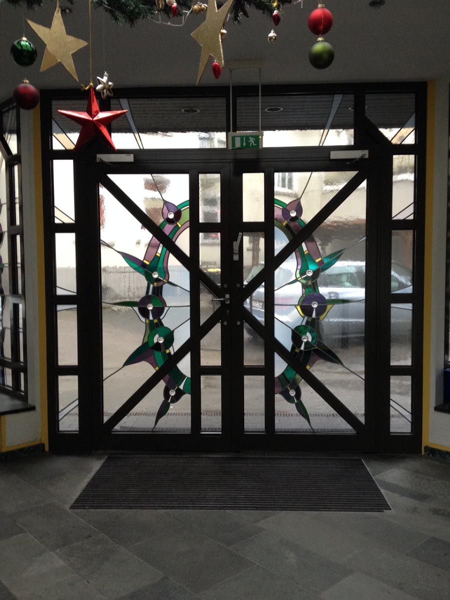 Eine Buntglastür mit Weihnachtsdekorationen, die von der Decke hängen