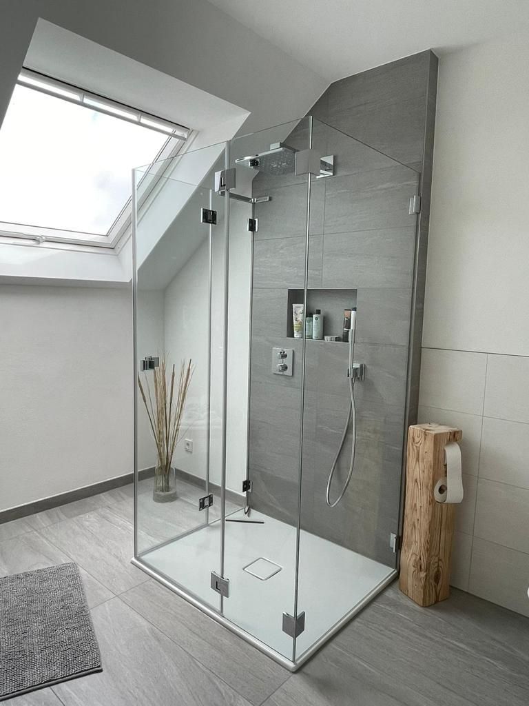 Ein Badezimmer mit ebenerdiger Dusche, mit Glaswand, und Oberlicht.