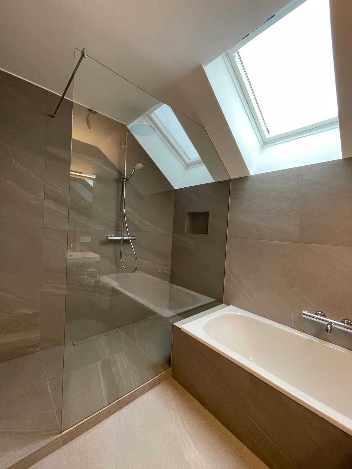 Ein Badezimmer mit ebenerdiger Dusche, mit Glaswand, und Badewanne