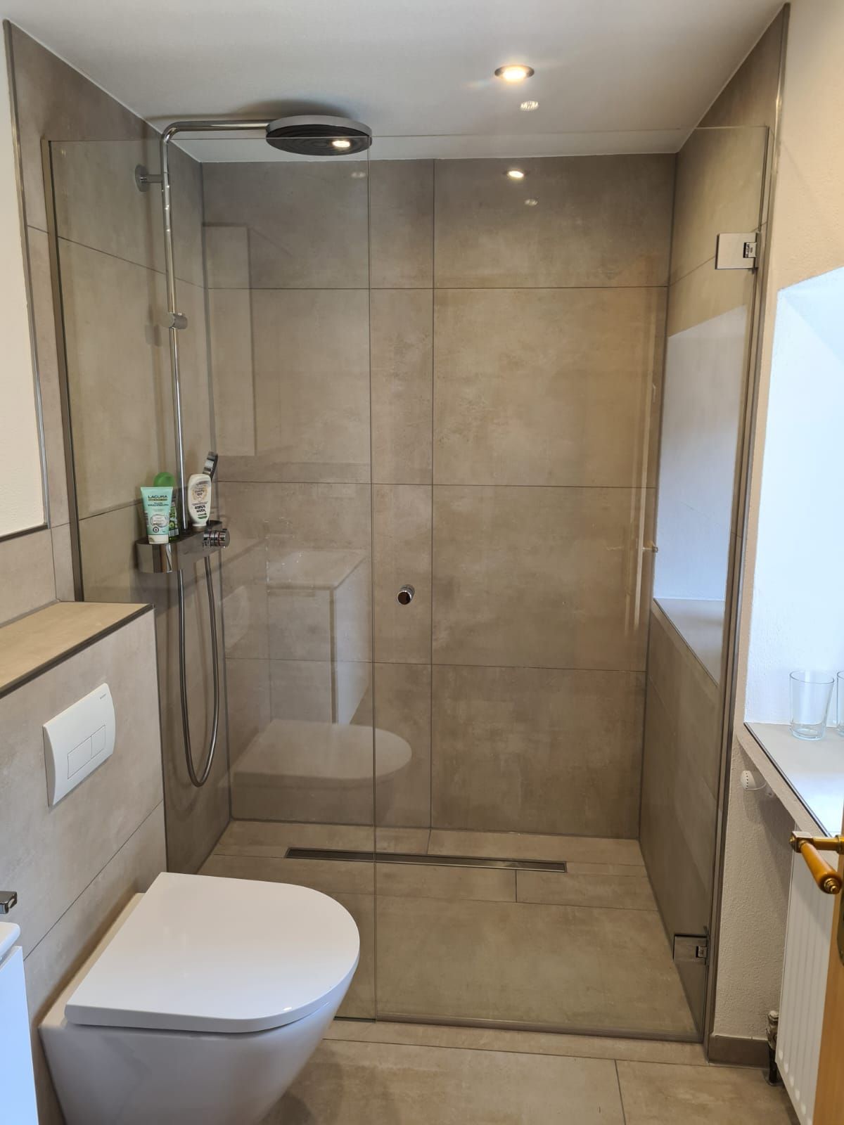 Ein Badezimmer mit Toilette und ebenerdiger Dusche.