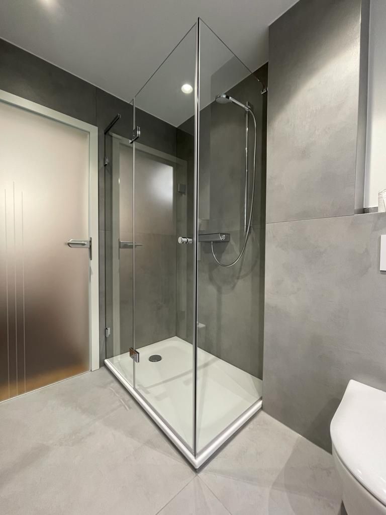 Ein Badezimmer mit ebenerdiger Dusche und Toilette.