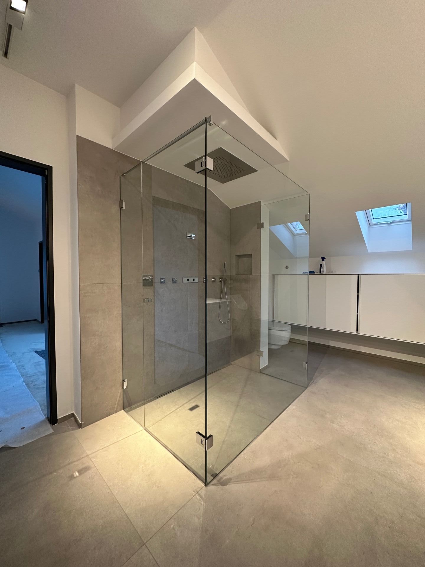 Ein Badezimmer mit ebenerdiger Dusche und Toilette.