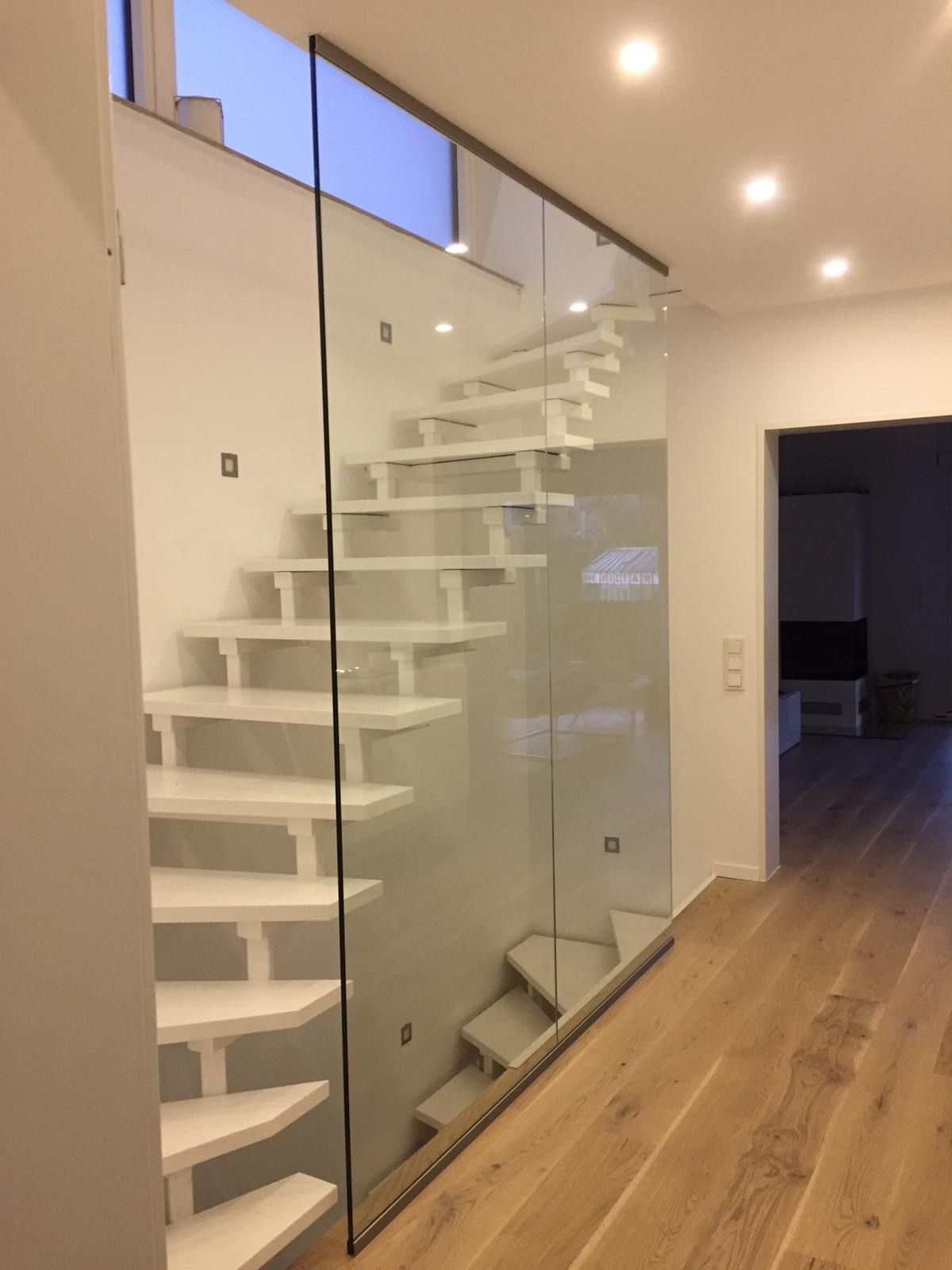 Eine weiße Treppe mit einem Glasgeländer in einem Flur