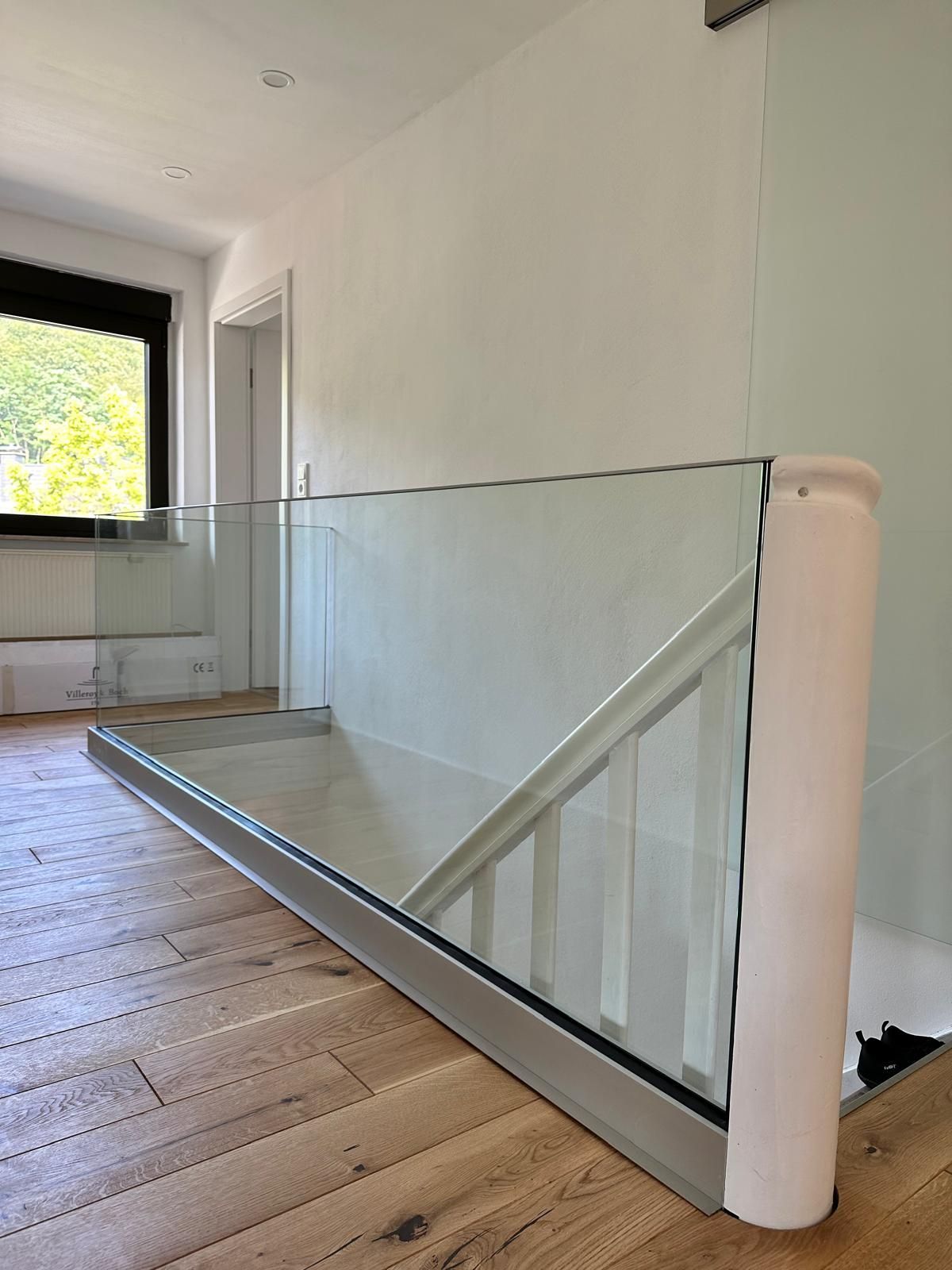 Eine Treppe mit einem Glasgeländer und Holzböden in einem Haus.
