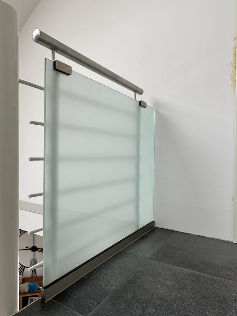 Eine Treppe mit einem Glasgeländer und einem Edelstahlgeländer.