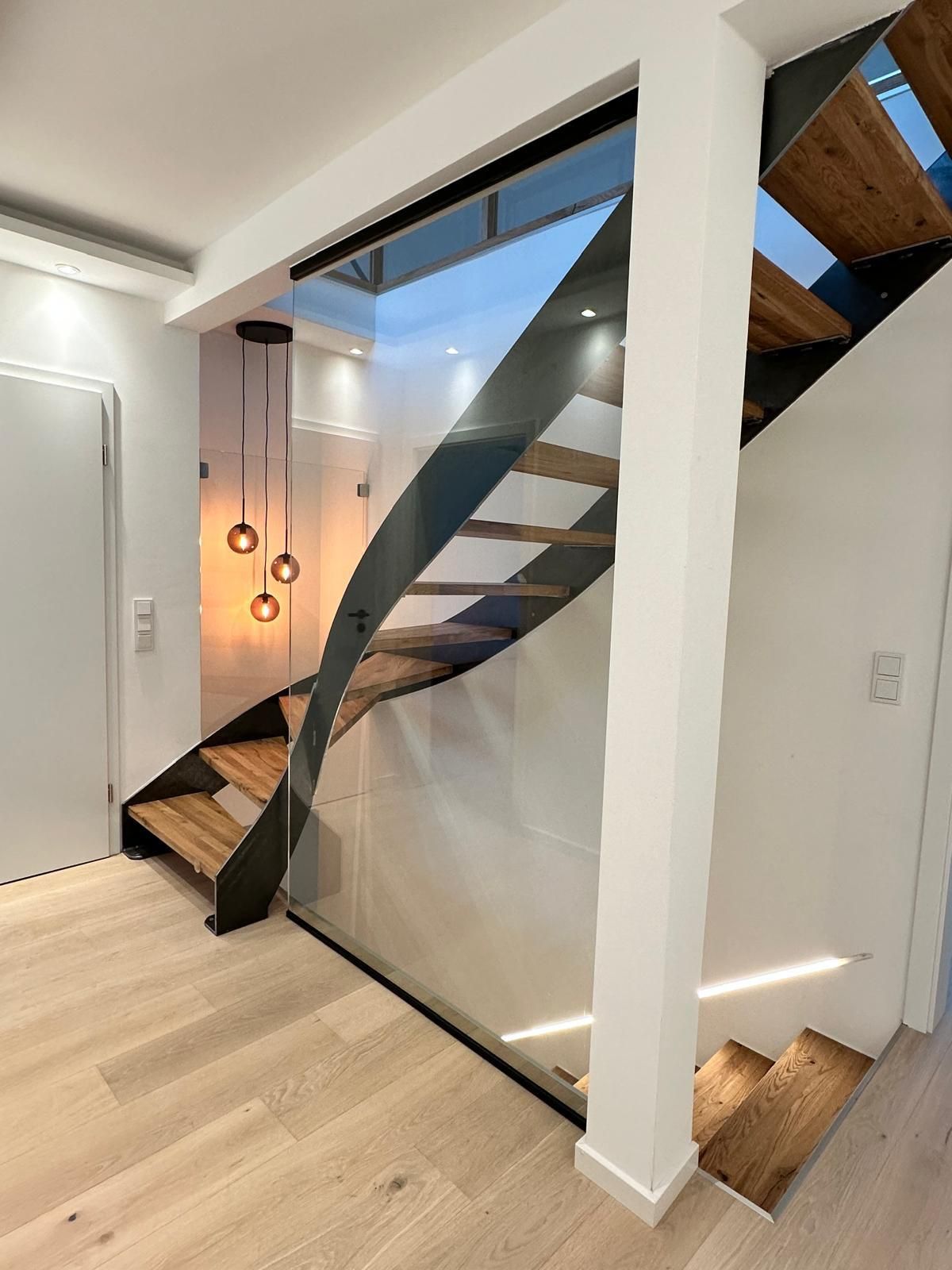 Eine moderne Treppe mit Holzstufen und einem Glasgeländer.