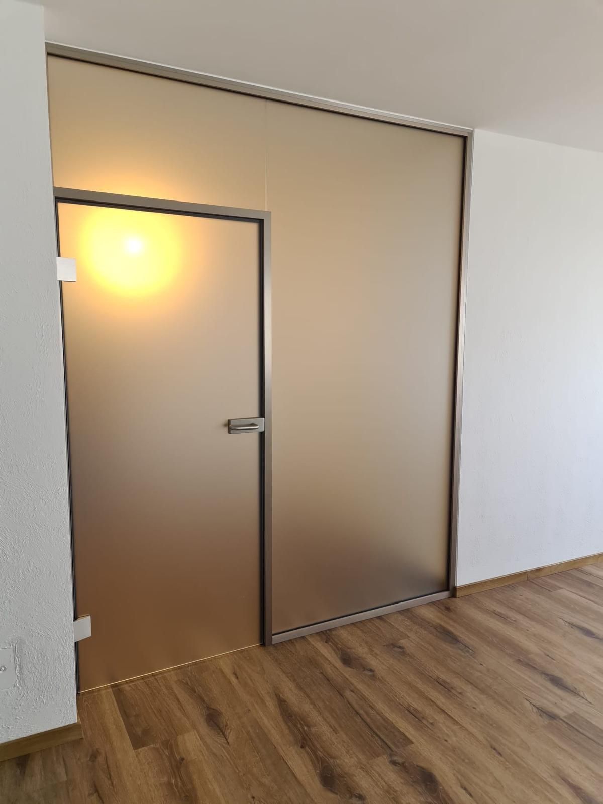 Ein Raum mit einer Glastür und einem Holzboden.