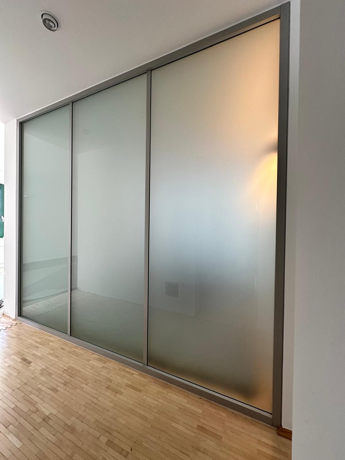 Ein Raum mit einer Glasschiebetür und einem Holzboden.