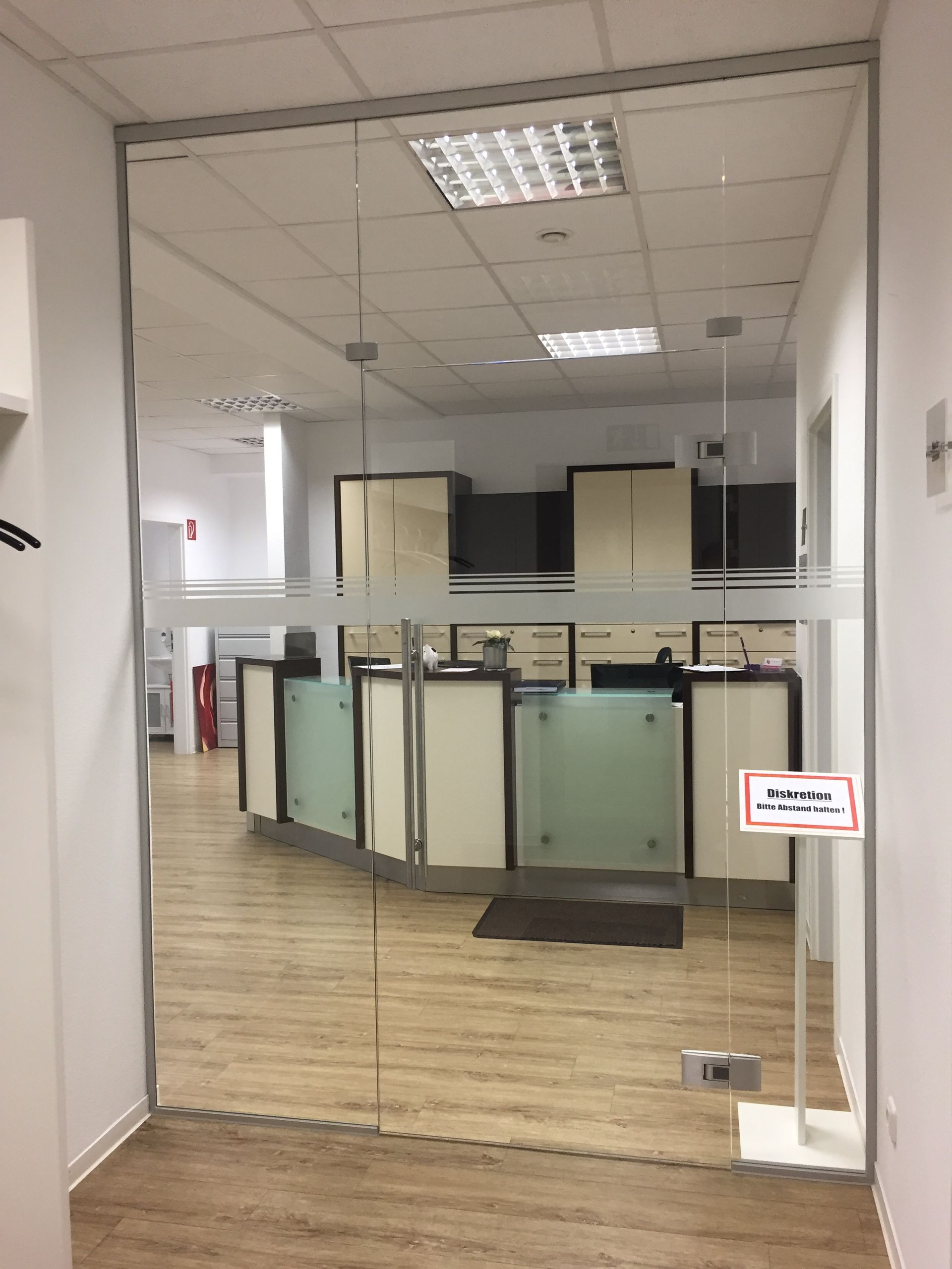 Ein Flur mit einer Glastür, die zu einem Rezeptionstresen führt