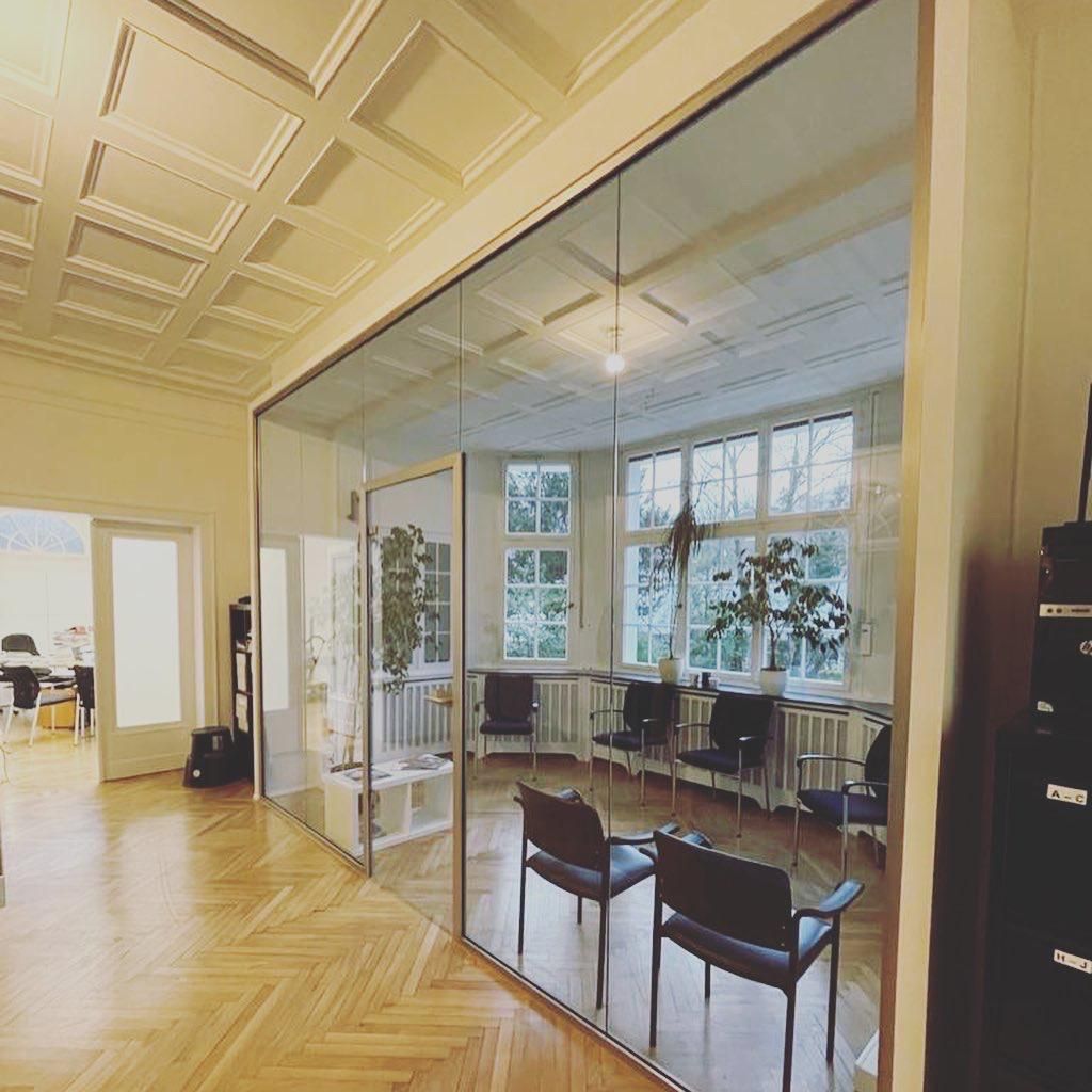 Ein Wartezimmer mit Stühlen und einer Glaswand