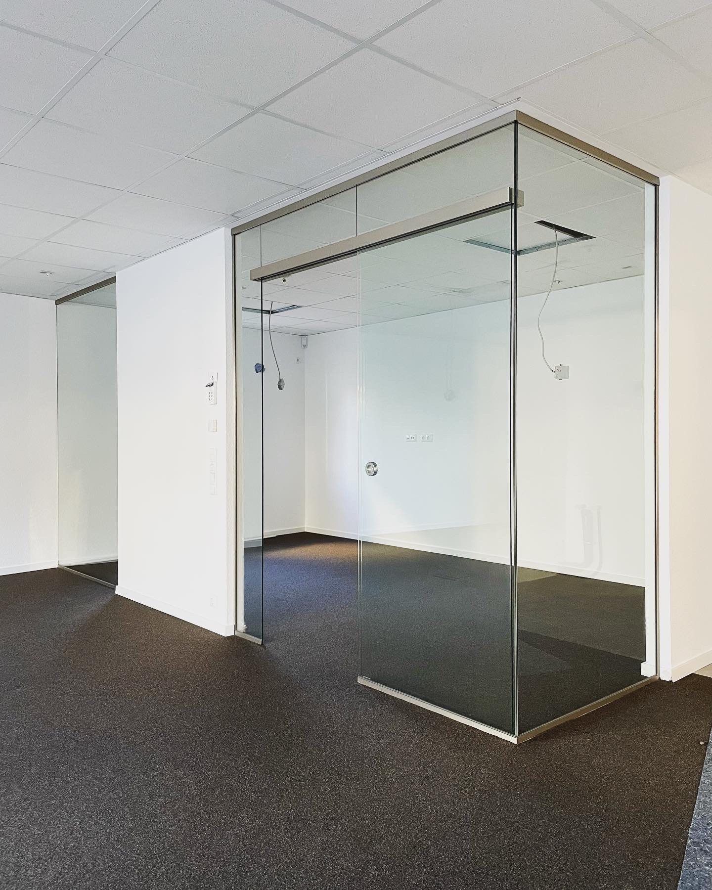 Ein leerer Raum mit einer Glaswand und einem braunen Teppich.