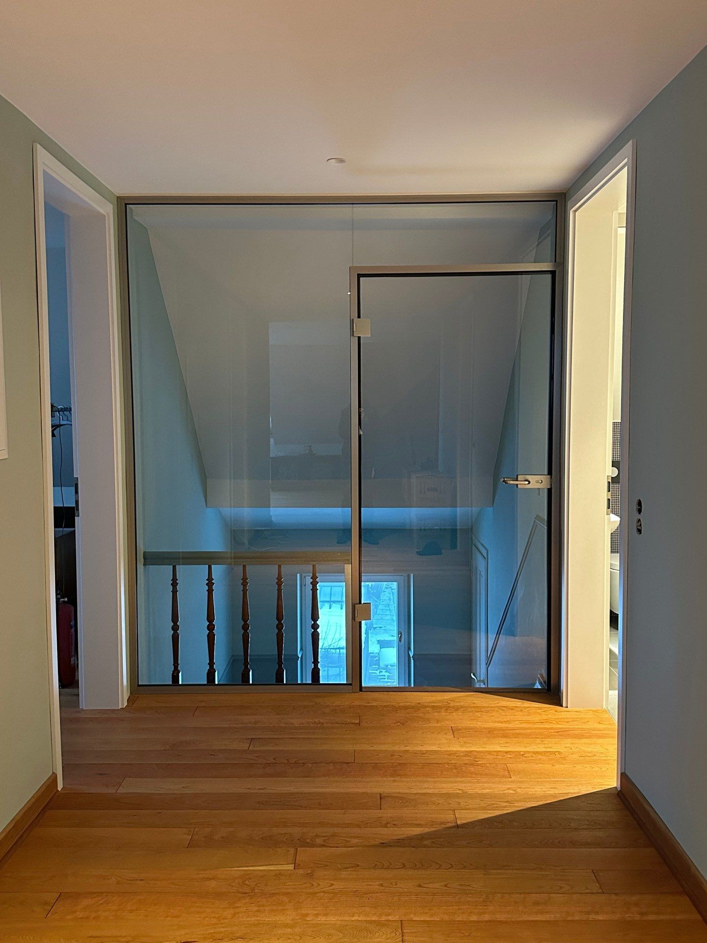 Ein Flur mit Holzboden und einer Glastür, die zu einer Treppe führt.