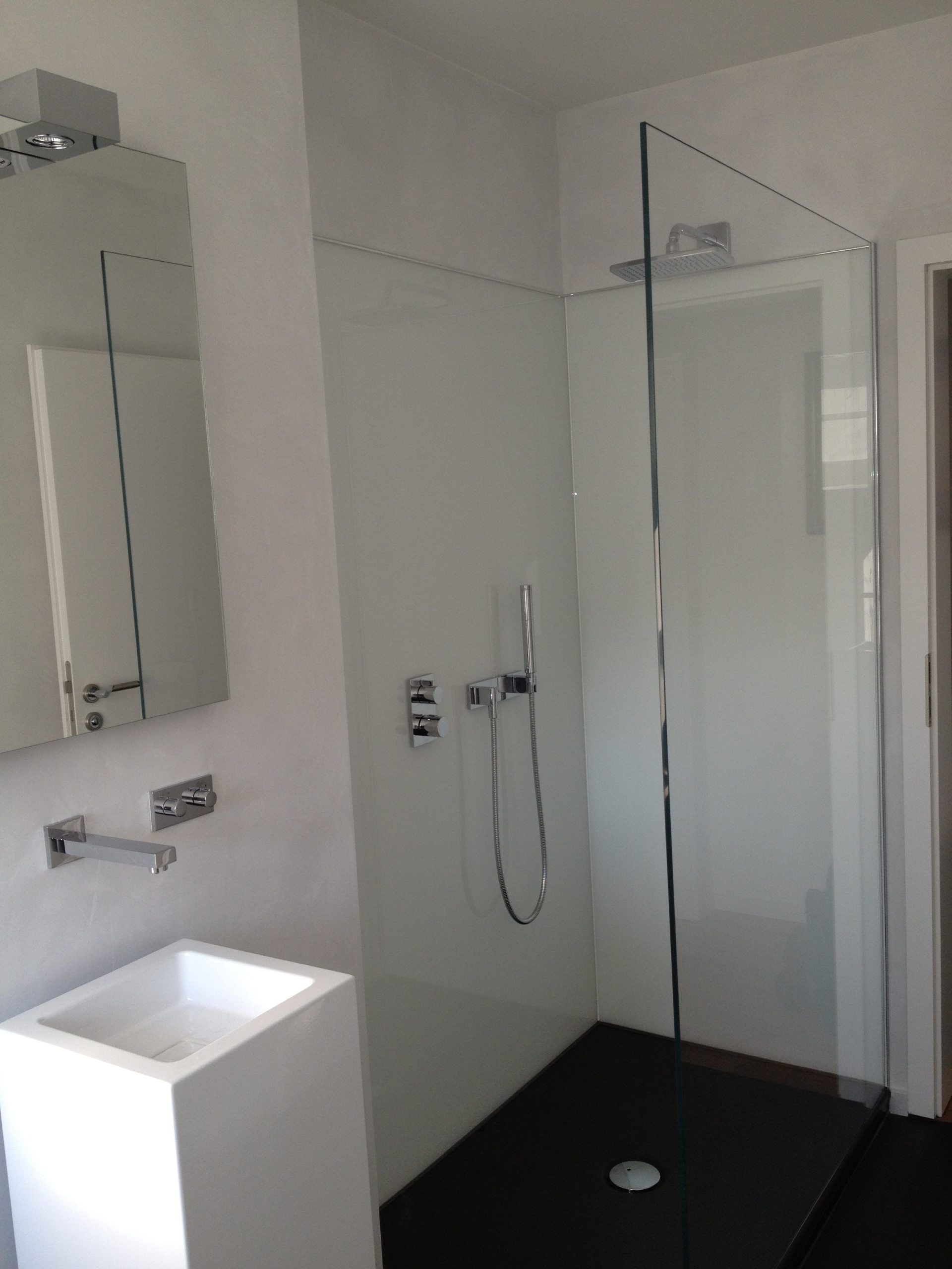 Ein Badezimmer mit ebenerdiger Dusche, Waschbecken und Spiegel.