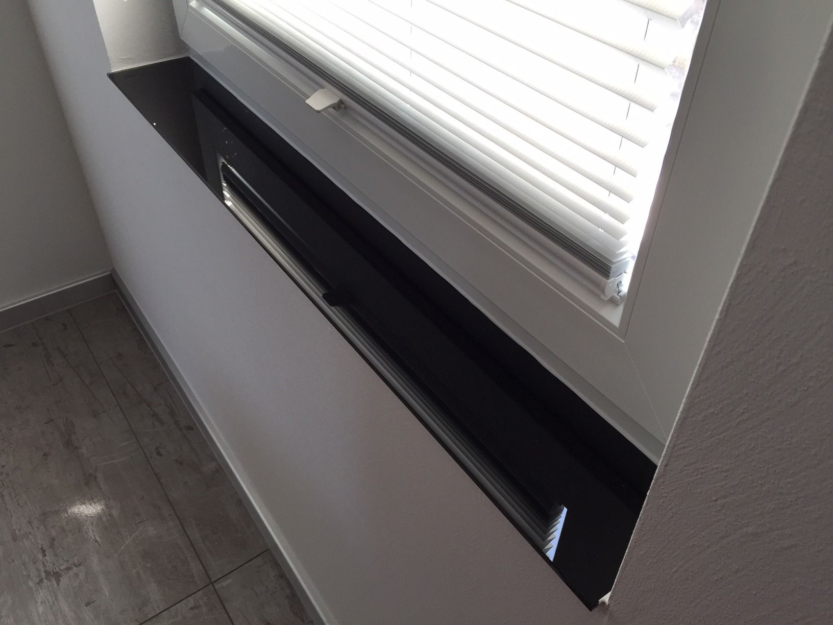 Ein Fenster mit Jalousien und einer schwarzen Fensterbank