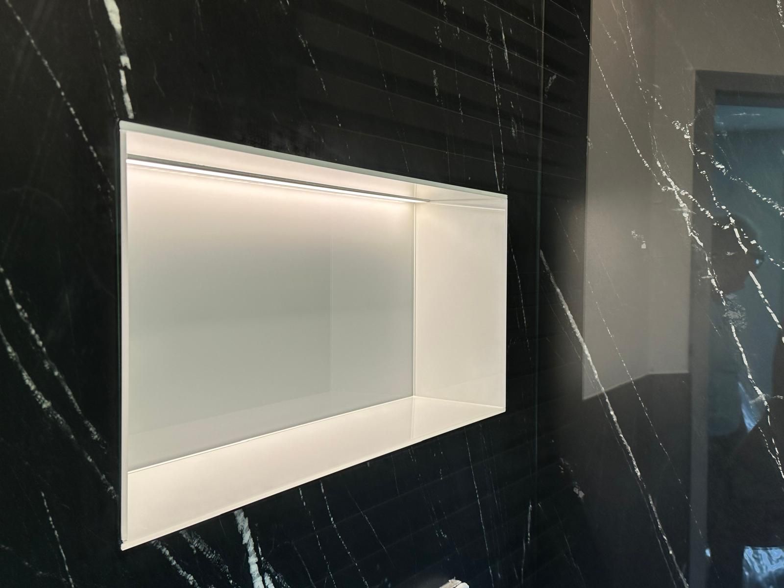 Ein Badezimmer mit einer schwarzen Marmorwand und einem Regal mit weißer Glasrückwand
