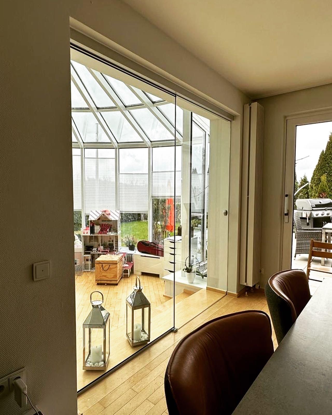 Ein Wohnzimmer mit Tisch und Stühlen und einem Gewächshaus im Hintergrund.