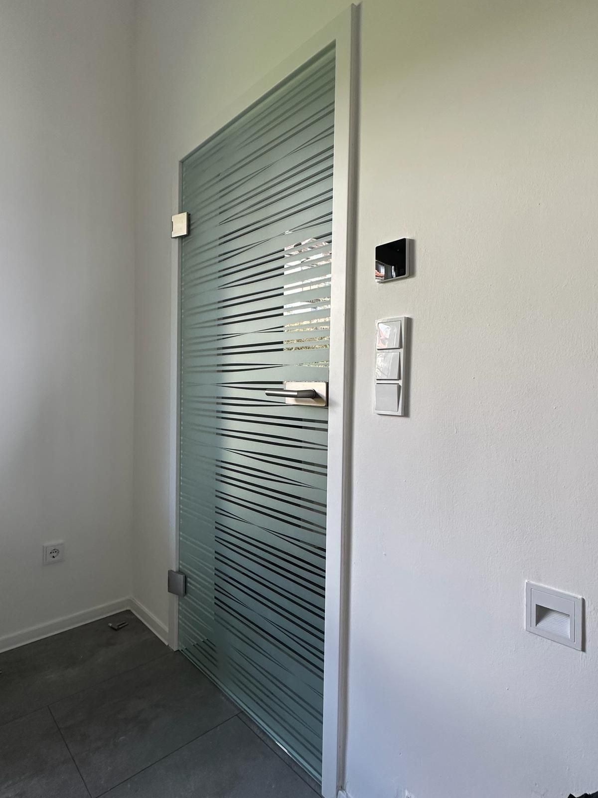 In einem Raum befindet sich eine Glastür mit einem Streifenmuster.