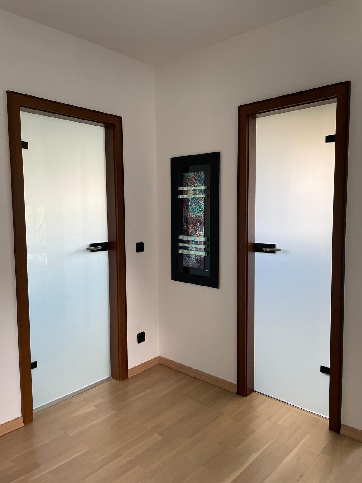Ein Raum mit zwei Glastüren und einem Bild an der Wand.