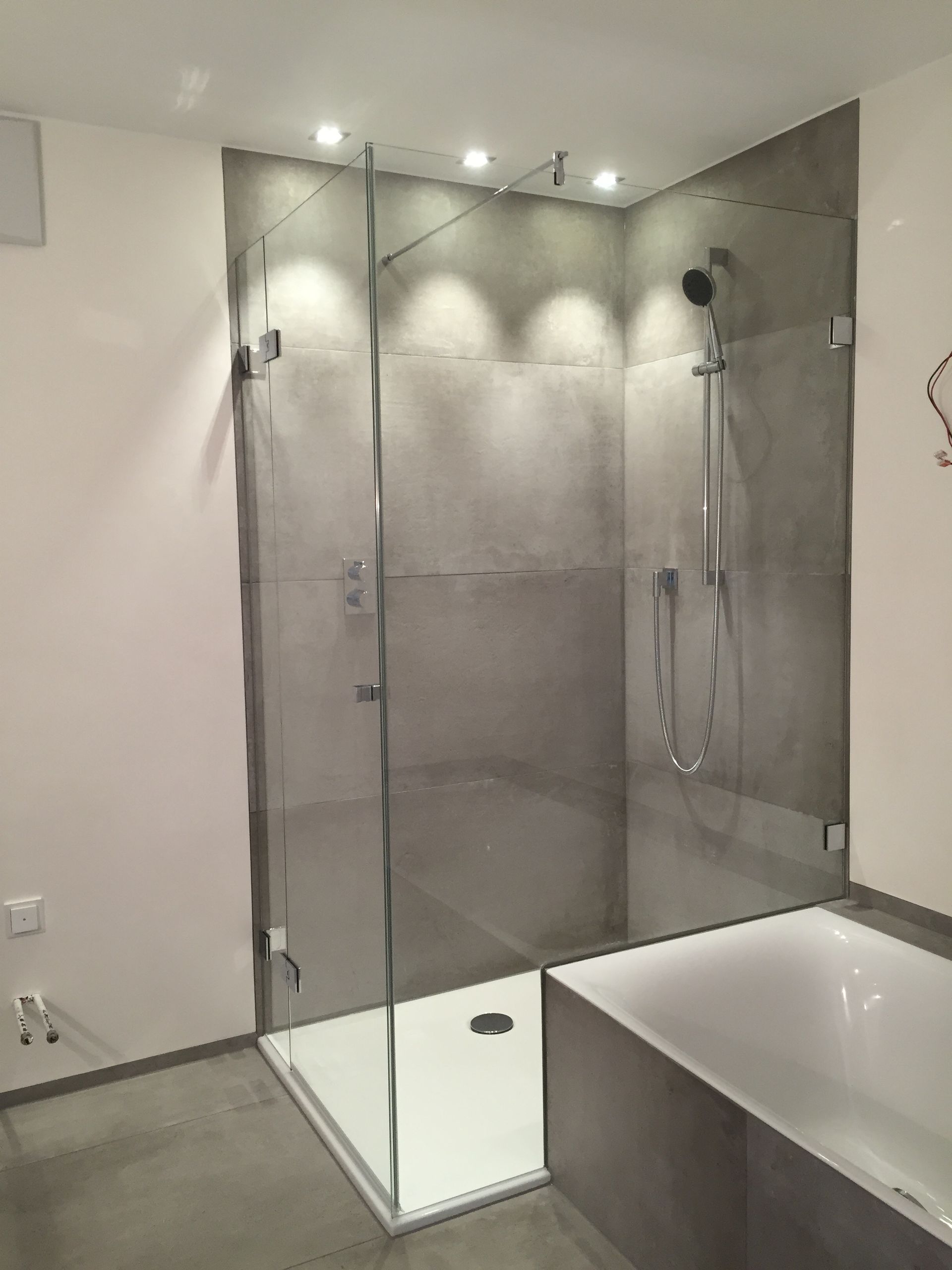 Ein Badezimmer mit ebenerdiger Dusche, mit Glaswand, und Badewanne.