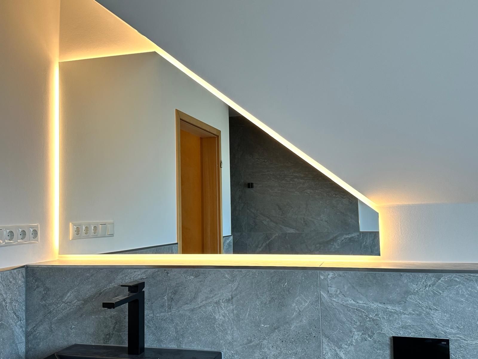 Ein Badezimmer mit großem beleuchtetem Spiegel und Waschbecken