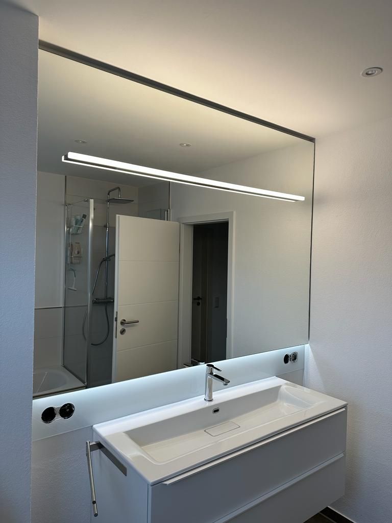 Ein Badezimmer mit Waschbecken und großem Spiegel.