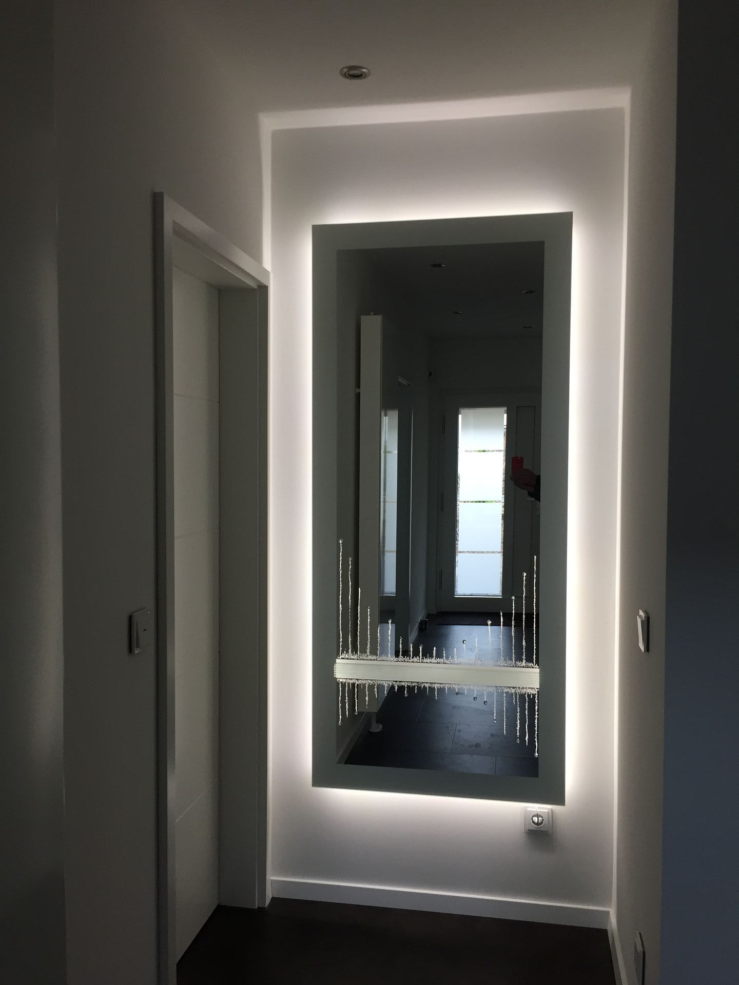 Ein Badezimmer mit großem Spiegel, indirekter Beleuchtung und Waschbecken